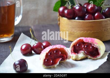 Torte russe fatte in casa di ciliegio su sfondo di legno e tazza di tè. Con ciliegia nel cesto Foto Stock