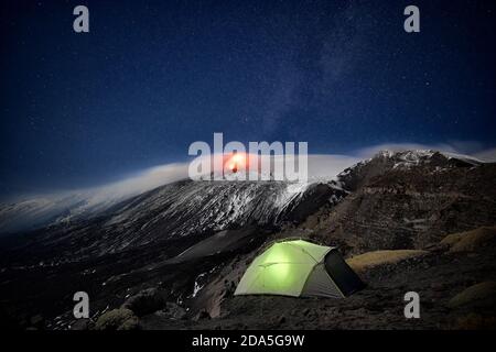 Tenda illuminata sotto eruzione vulcano etna e cielo stellato, Sicilia Foto Stock