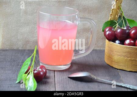 Kissel con ciliegie in un bicchiere su un vecchio sfondo di legno, tradizionale russia o polonia bevanda, gelatina di frutti di bosco, mousse, estate rosa bevanda Foto Stock