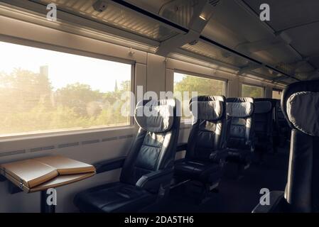 Interni in treno di prima classe con sedili vuoti, in movimento, in giornata di sole. Treno passeggeri, espresso interurbano tedesco. Trasporto pubblico in business class Foto Stock