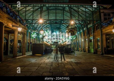 Londra, Regno Unito. 8 novembre 2020. Una coppia ammira le luci e le decorazioni natalizie del Covent Garden, ma la zona è molto tranquilla la sera il giorno 3 del UKís 2° Lockdown Credit: SOPA Images Limited/Alamy Live News Foto Stock