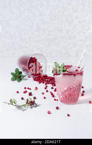 Cocktail rosa aspero di mirtillo con bacca rossa, cubetti di ghiaccio e paillette su tavola di legno bianco, spazio per la copia, vista dall'alto. Foto Stock