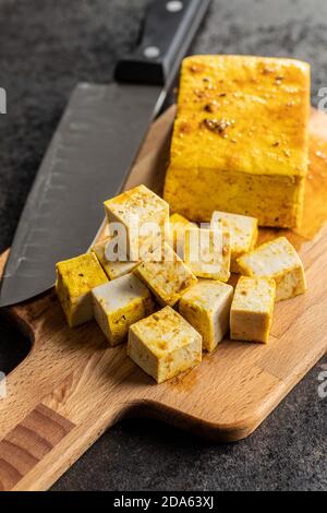 Morse di tofu marinato su tagliere. Foto Stock