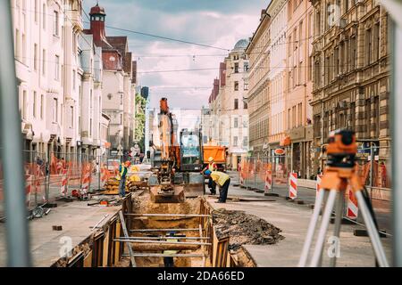 Riga, Lettonia. I lavoratori sono impegnati a riparare le comunicazioni sulla strada Aleksandra Caka con un escavatore Foto Stock