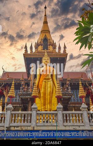 Una figura di un Buddha in piedi sul tetto, la sala del Buddha di Wat Lat (Lad) Phrao, Bangkok, Thailandia, posta contro un cielo drammatico (alterato digitalmente) Foto Stock