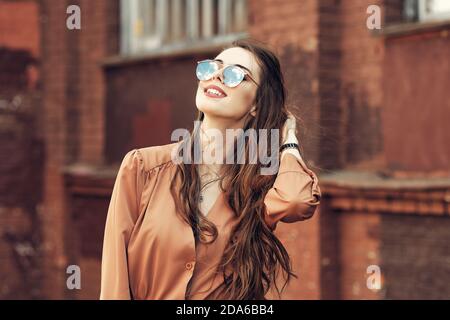 Ritratto di giovane donna con lunghi capelli ricci in occhiali da sole Foto Stock