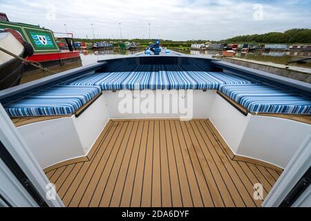 Vista ad angolo basso dell'impressionante area salotto, rivestita in materiale a righe blu, alla prua di un nuovo narrowboat ormeggiato in un porto turistico nel Regno Unito Foto Stock