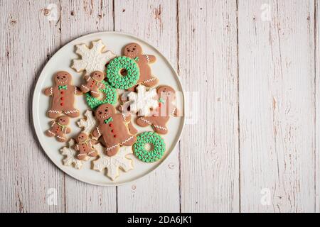 Piatto di biscotti di pan di zenzero di Natale decorato uomo di pan di zenzero con fiocchi di neve e biscotti altri su una superficie di legno testurizzata Foto Stock