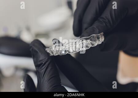 Primo piano di una mano di donna che mette un allineatore trasparente in denti. Foto Stock