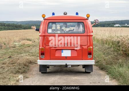 Coppia di nozze in Oldtimer VW T1 fuoco motore rosso fuoco macchina classica auto guida sulla strada. Foto Stock