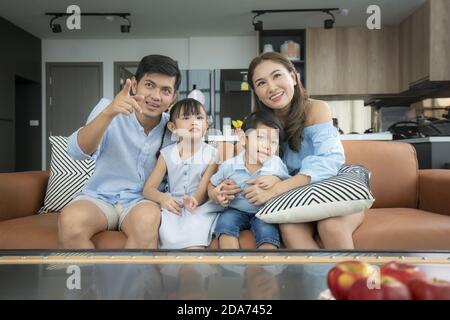 Asian felice famiglia seduta e guardando la televisione in soggiorno a casa e passato tempo di qualità insieme per attività in vacanza giorno, vacanza, happi Foto Stock