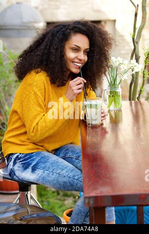 Ritratto laterale di una giovane donna sorridente che beve mojito a. caffetteria all'aperto Foto Stock