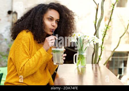 Closeup ritratto di pessiva donna africana che beve mojito all'aperto caffè Foto Stock
