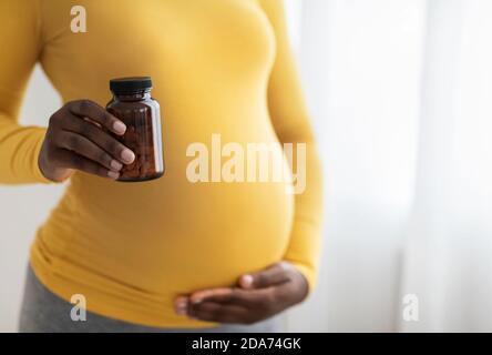 Irriconoscibile afroamericano che si aspetta donna raccomandando integratori per future madri Foto Stock