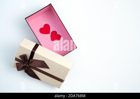 Aprire la confezione regalo con due cuori rossi sulla parte inferiore su uno sfondo chiaro. Foto Stock