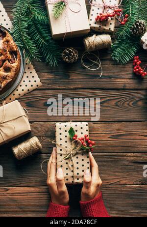 Vista dall'alto delle mani femminili che tengono un regalo di Natale avvolto in carta artigianale Foto Stock