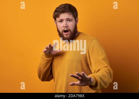 Concetto di linguaggio del corpo. Uomo spaventato con espressione spaventosa, gesti con palme, fa segno di difesa, eslaim con espressione stupefacente, vestito Foto Stock