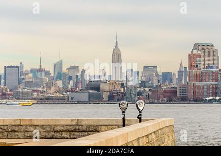 Due Binocoli a gestione di moneta con vista sugli edifici di Manhattan, i grattacieli e le torri. Vista dalla piattaforma di osservazione di Ellis Island. New York City, Stati Uniti Foto Stock