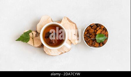 Tè Chaga e pezzi di funghi Chaga su sfondo bianco. Infusione organica con pezzi di chaga. Vista dall'alto. Foto Stock