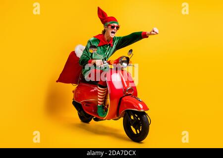 Ritratto del suo bel ragazzo allegro ed energico divertente il ciclomotore elf offre regali veloci da urlo a dicembre vendita isolata Foto Stock