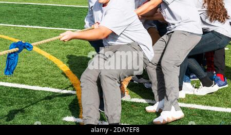 Adolescenti che tirano una corda durante un rimorchiatore di gioco di guerra in classe palestra. Foto Stock