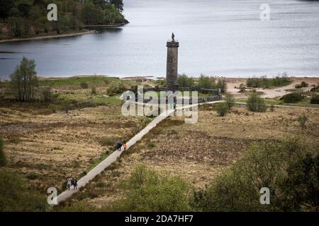 I turisti camminano lungo il sentiero per il Glenfinnan Monument e Loch Shiel oltre, visto da una vicina collina, Glenfinnan, Scozia. Foto Stock