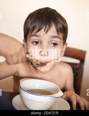 Il ragazzino mangia con un cucchiaio da un piatto Foto Stock