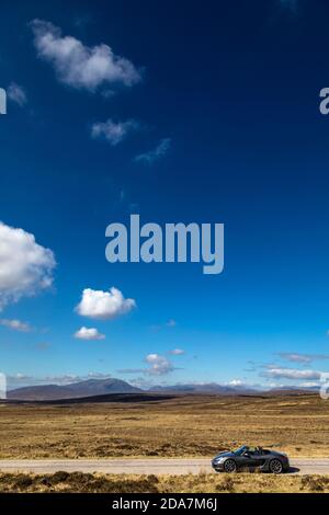 Porsche Boxster sportscar da solo sulla strada nel vasto vuoto del 'Flow Country' di Sutherland, Scozia. Foto Stock