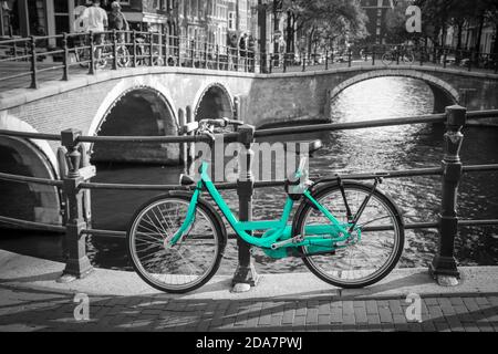 Una bici azzurra per le strade di Amsterdam. Simbolo per il trasporto urbano pulito ed ecologico. Isolato su sfondo bianco e nero. Foto Stock