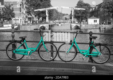 Due moto azzurre fresche per le strade di Amsterdam. Simbolo per il trasporto urbano pulito ed ecologico. Isolato su sfondo bianco e nero. Foto Stock