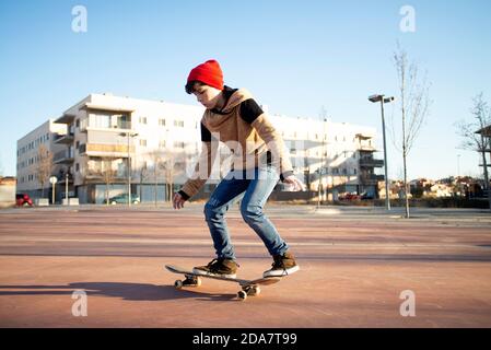 Skateboarder maschile a cavallo e pratica skateboard in città all'aperto Foto Stock