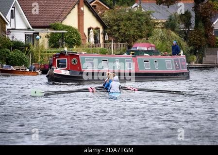Vogatori che costolano un narrowboat sul Tamigi vicino a Weybridge In Surrey Foto Stock