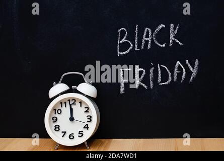 Testo del black friday scritto su lavagna e sveglia Foto Stock