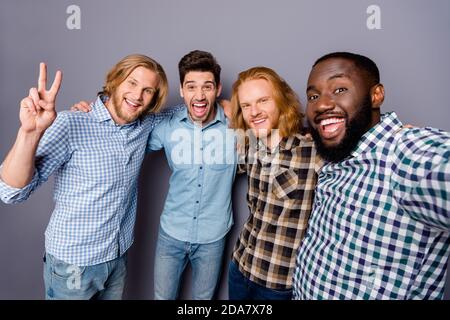 Autoritratto di quattro simpatici allegri allegri allegri, allegri, positivi abbracciando avere divertente riunione mostrando v-segno isolato su viola grigio Foto Stock