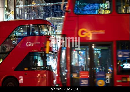 LONDRA - 3 NOVEMBRE 2020: Autobus a due piani Red London che passano di fronte alle decorazioni natalizie di Oxford Street di notte Foto Stock