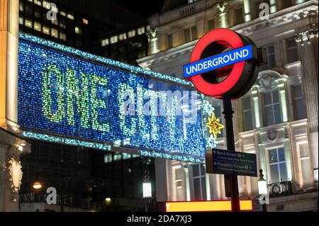 LONDRA - 3 NOVEMBRE 2020: Insegna della metropolitana di Londra ad Oxford Circus con decorazioni natalizie illuminate di Oxford Street fuori dal fuoco nello sfondo Foto Stock