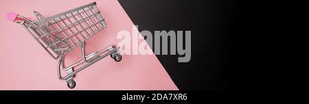 Mini carrello per lo shopping su sfondo rosa e nero. Foto Stock