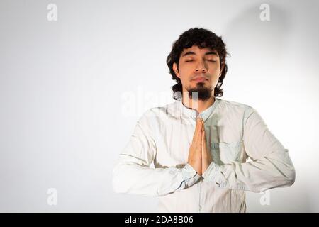 Giovane uomo ispanico che indossa abiti casual su sfondo bianco meditando tranquillamente con gli occhi chiusi Foto Stock