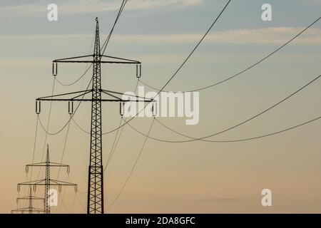 Poli di potenza con linee elettriche al tramonto, gradiente luminoso dal giallo al blu, linee elettriche stanno andando all'orizzonte, linee elettriche sono essenziali nel nostro dai Foto Stock