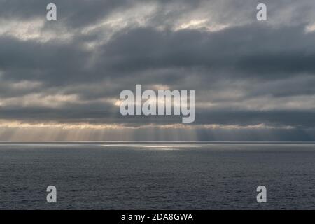 Raggi del sole che scendono dalle nuvole sull'oceano Foto Stock