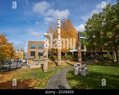 Kwakiutl stile riconciliazione totem pole e Coast Salish Welcome Posts al di fuori del Vancouver School Board edificio, Vancouver, BC, Canada Foto Stock