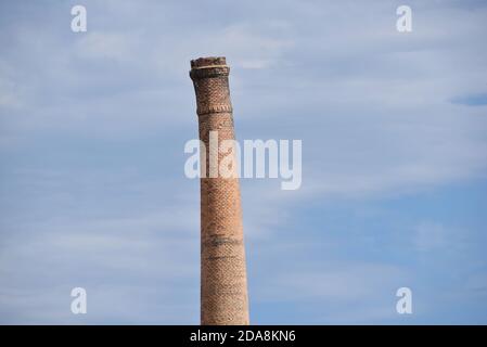 Un vecchio camino in mattoni si affaccia in modo sfacciato contro un cielo blu, in questa foto scattata a Oliva, in Spagna Foto Stock