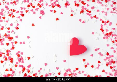 Cuore rosso circondato da piccoli cuori su uno sfondo chiaro. Foto Stock
