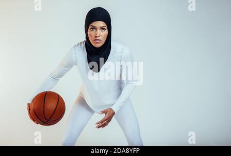 Atleta femminile che pratica il basket con la massima determinazione. Ritratto dell'atleta di basket su sfondo bianco. Foto Stock