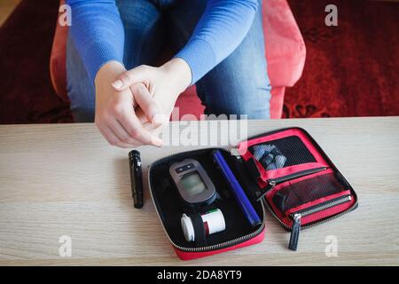 La donna si sta preparando a controllare il livello di glucosio nel suo sangue, il diabete impostato sul tavolo di casa Foto Stock