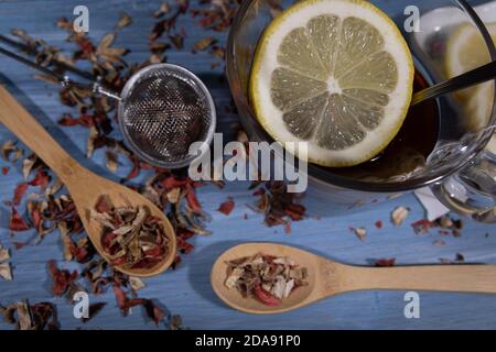 immagine di foglie di infusione e limone, cucchiaio di legno su blu tavolo in cucina Foto Stock