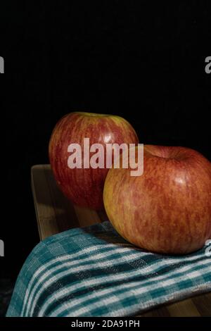 bella foto di mele rosse sul tavolo con tovaglia verde con sfondo nero Foto Stock