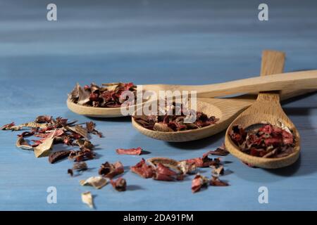 bella immagine di foglie di infusione su cucchiai di legno su blu tabella Foto Stock