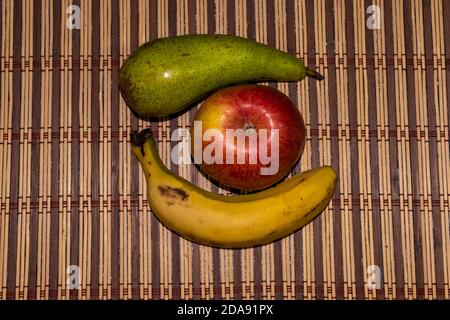 immagine ravvicinata di mele, pere e banane poste in un trivet sul tavolo Foto Stock