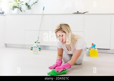 Giovane donna di pulizia e pavimento con straccio a casa. Foto Stock